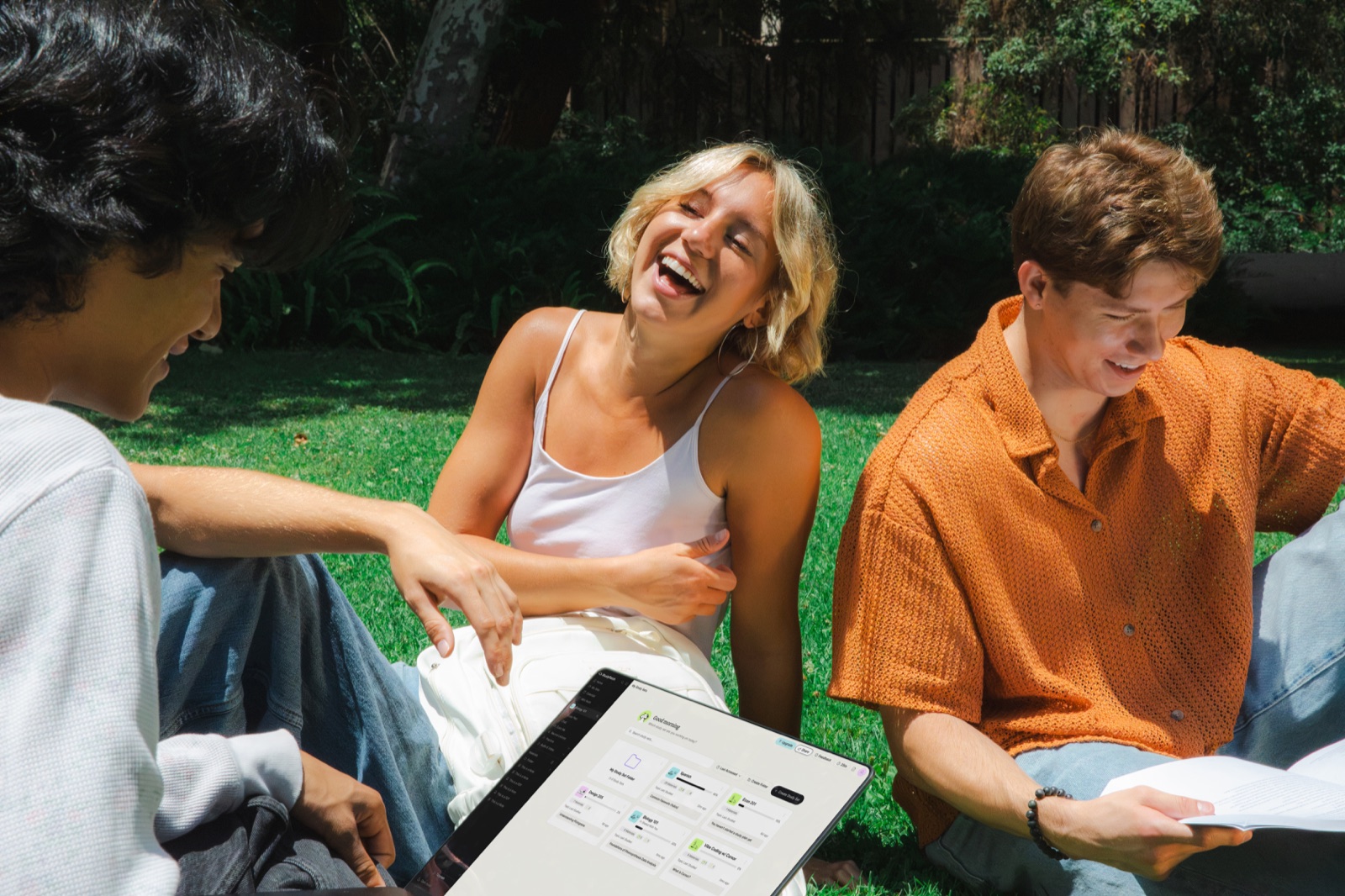 Student smiling while studying on a laptop outdoors in the grass